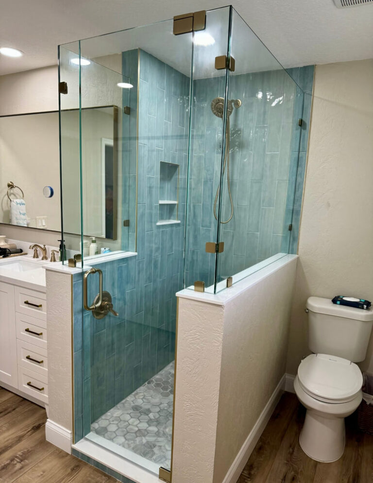 One hundred and eighty degree frameless shower enclosure with transome pivot door and brushed bronze hardware